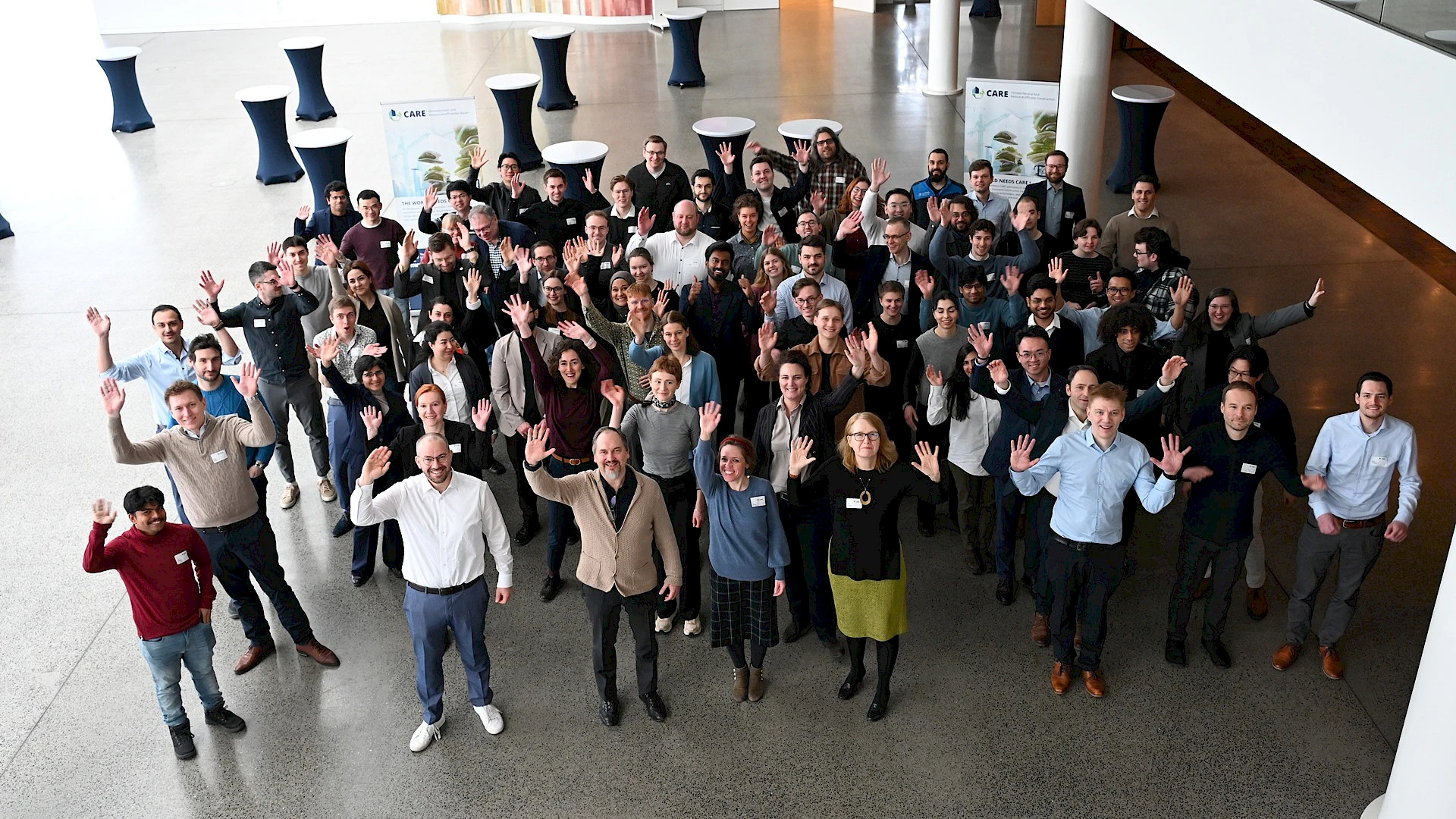 The 80 participants of the CARE Young Researchers’ Meeting held from February 9 to 11, 2026, in Würzburg. A group photo taken from above, with the participants waving at the camera.